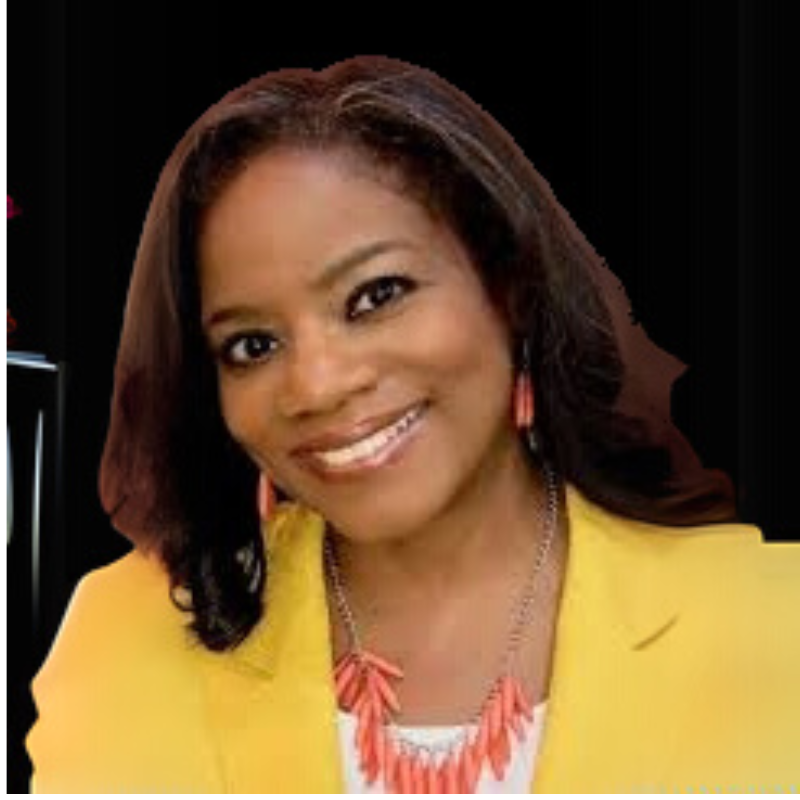 Wanda, a board member,A smiling person with dark hair wears a bright yellow blazer and a coral-colored statement necklace against a black background.