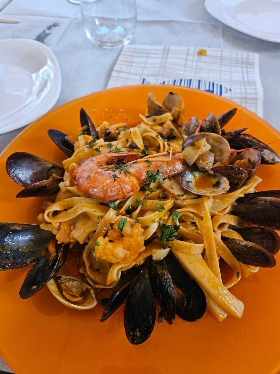 Piatto arancione di pasta ai frutti di mare con cozze e gamberi sul tavolo