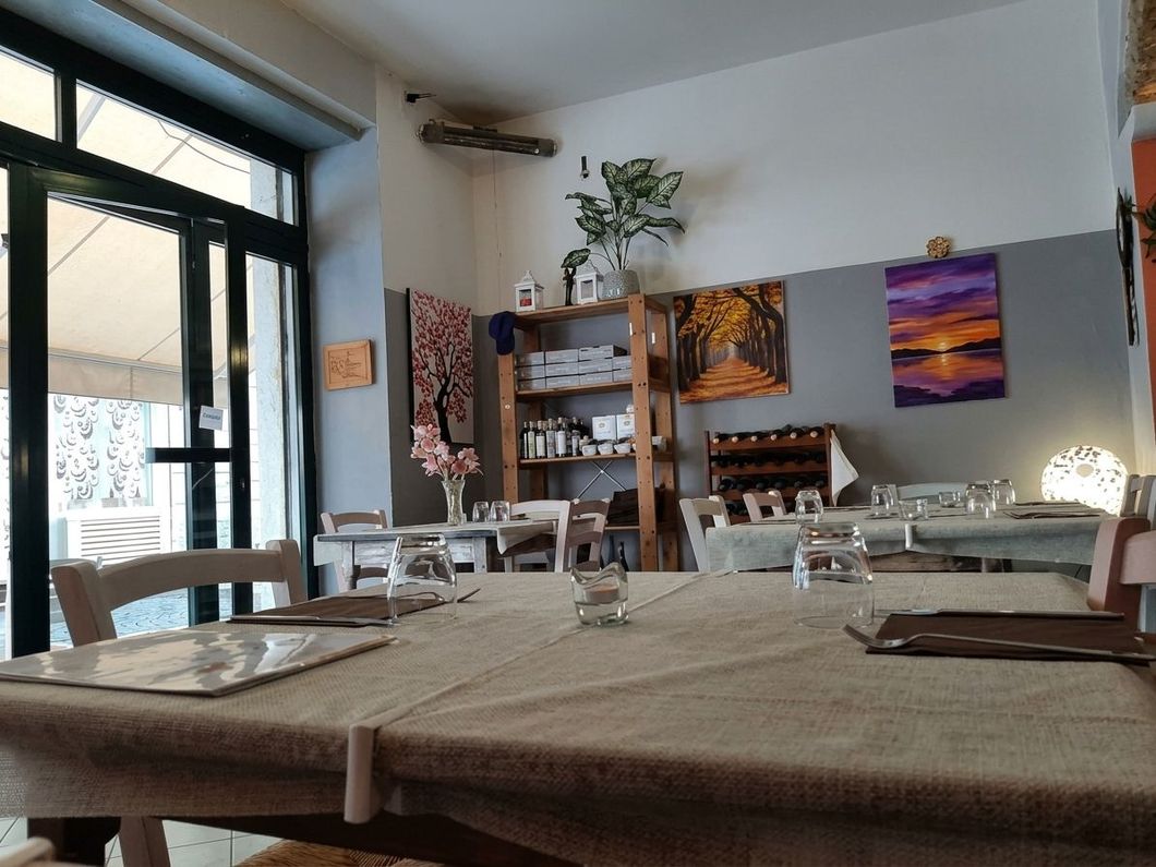 Accogliente interno di un caffè con tavoli in legno, scaffali, piante e opere d’arte colorate alle pareti vicino a una finestra