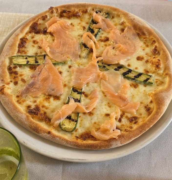 Pizza con salmone affumicato e zucchine grigliate, servita su un piatto