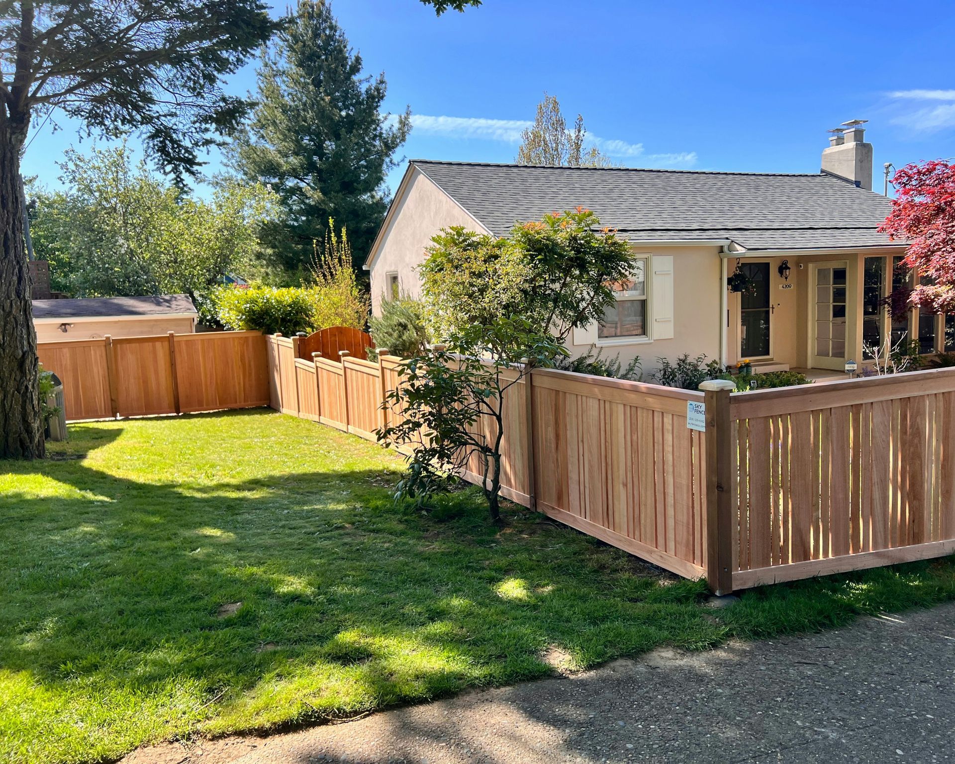 Sunny suburban house with tan fence, green lawn, and a paved driveway in Central PA