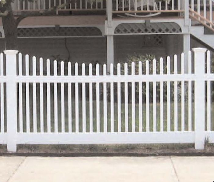 White picket fence in front of a house with a veranda.