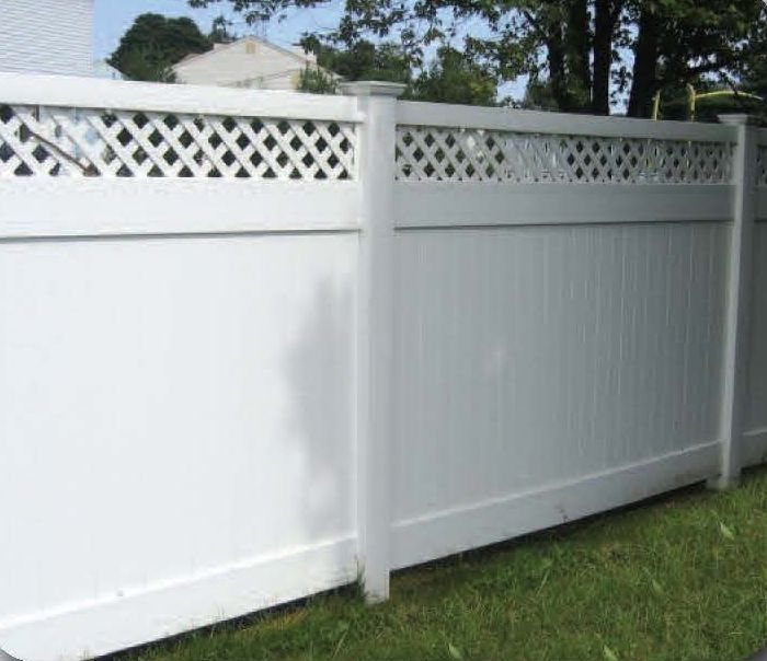 White vinyl fence with lattice top on green grass, residential setting.