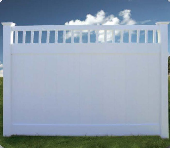 White vinyl privacy fence with a decorative top against a blue sky and green grass.