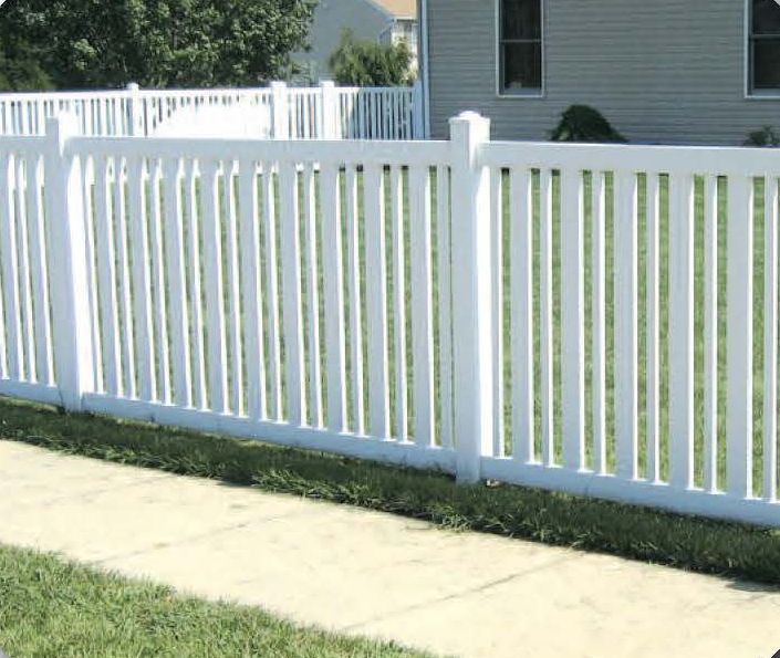White picket fence bordering a grassy lawn and sidewalk in front of a house.