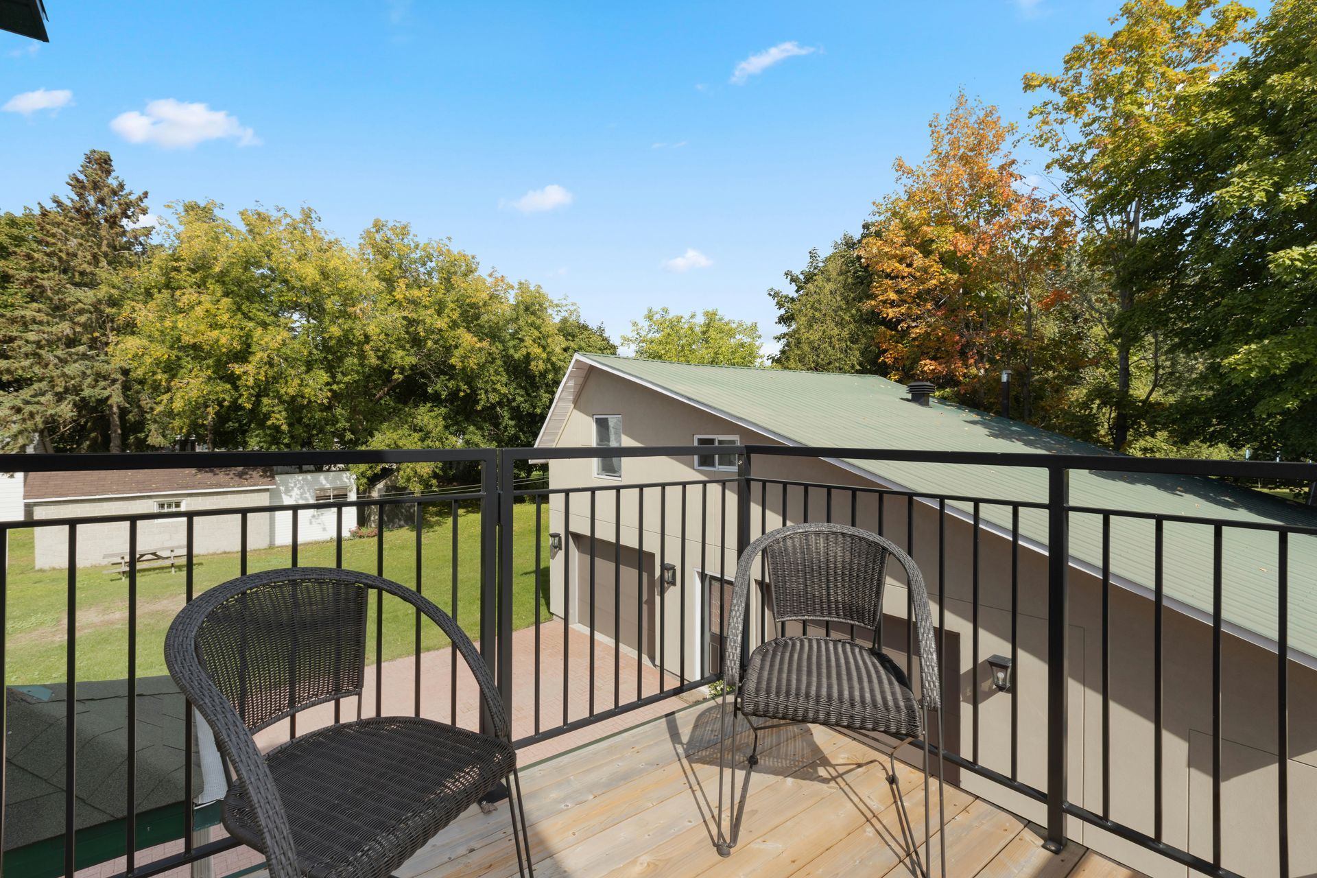 Balcony with two wicker chairs overlooking a green backyard and trees in Central PA