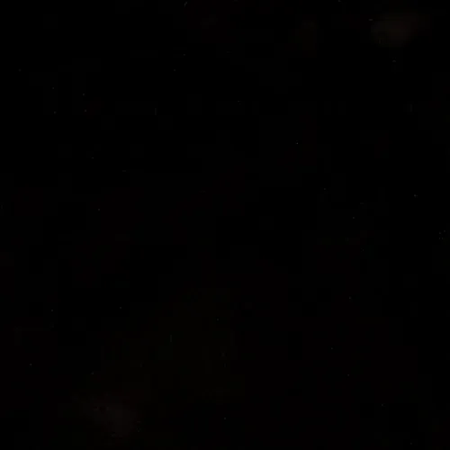 Dark, nearly black image with faint scattered red and orange specks, like distant lights or stars.