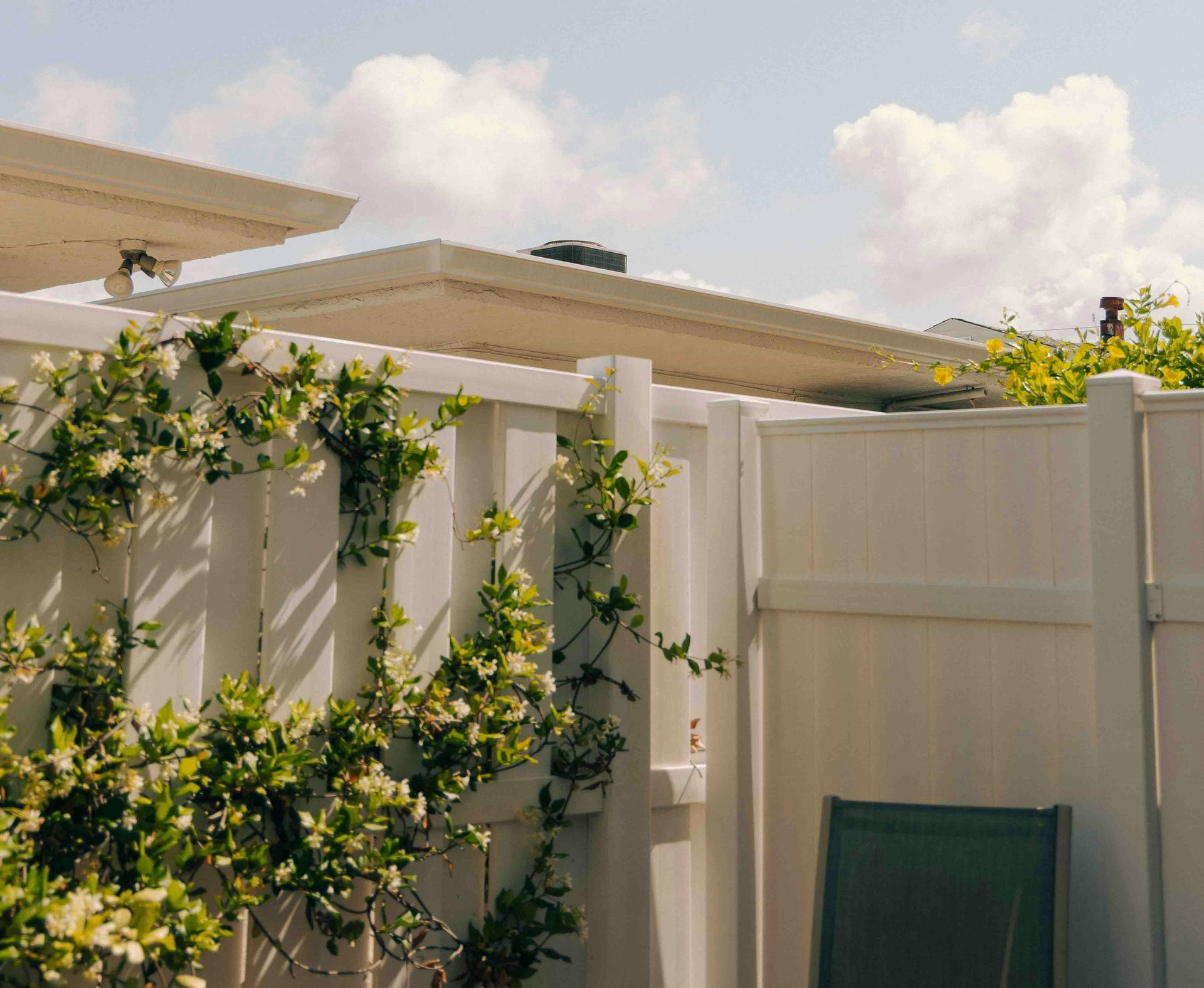 White vinyl fence with green vines and a beige patio awning under a cloudy sky in Central PA