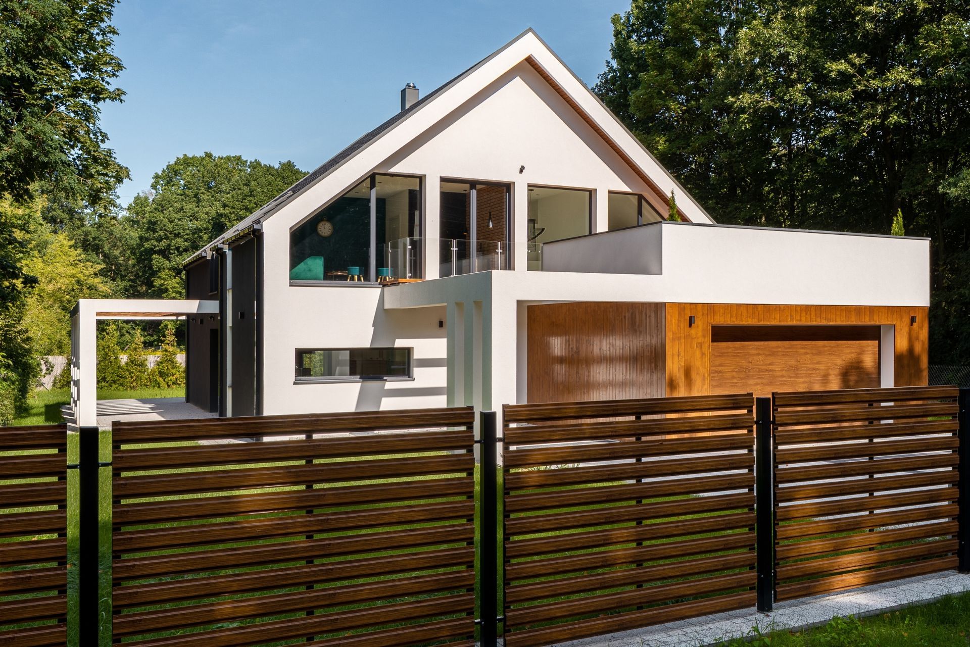 Modern white two-story house with wooden fence and green lawn under a clear sky in Central PA