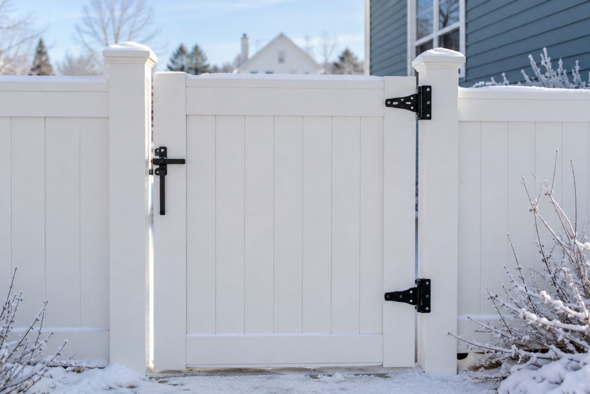 Snowy white picket gate in a fenced backyard, with black hinges and latches in Central PA
