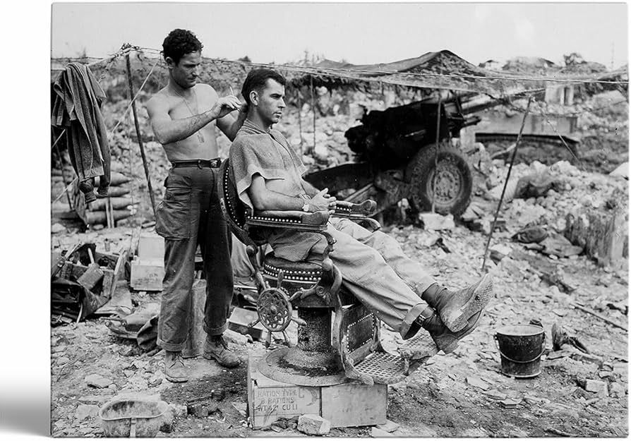 Soldier gets a haircut outdoors near rubble and an artillery gun.