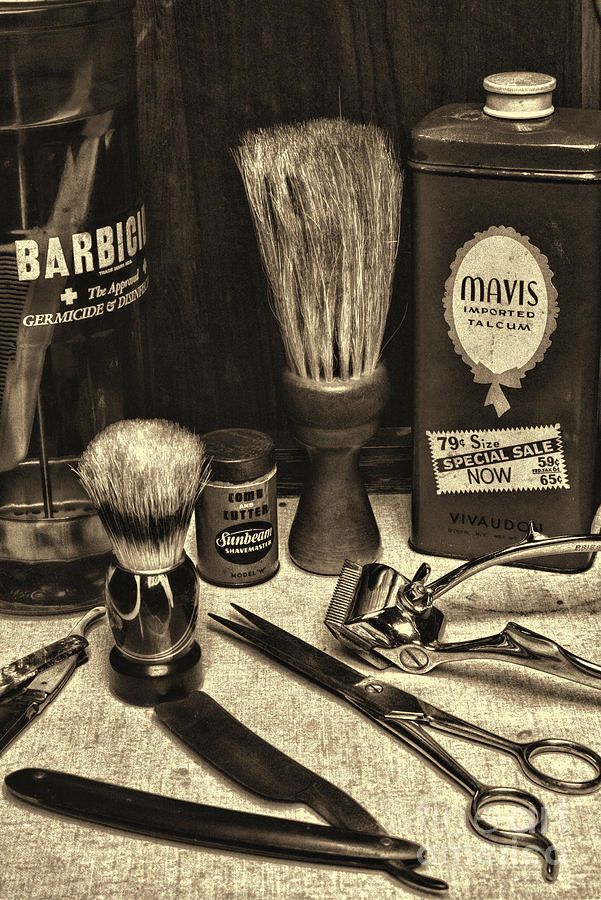 Antique barber tools, including brushes, razors, scissors, and clippers, arranged on a surface.