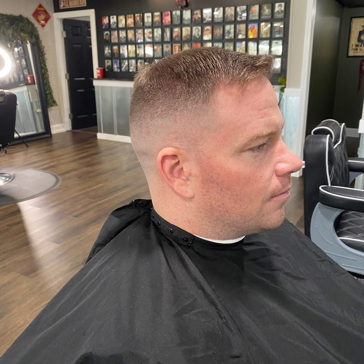 Man with a faded haircut in a barber shop, wearing a black barber cape.