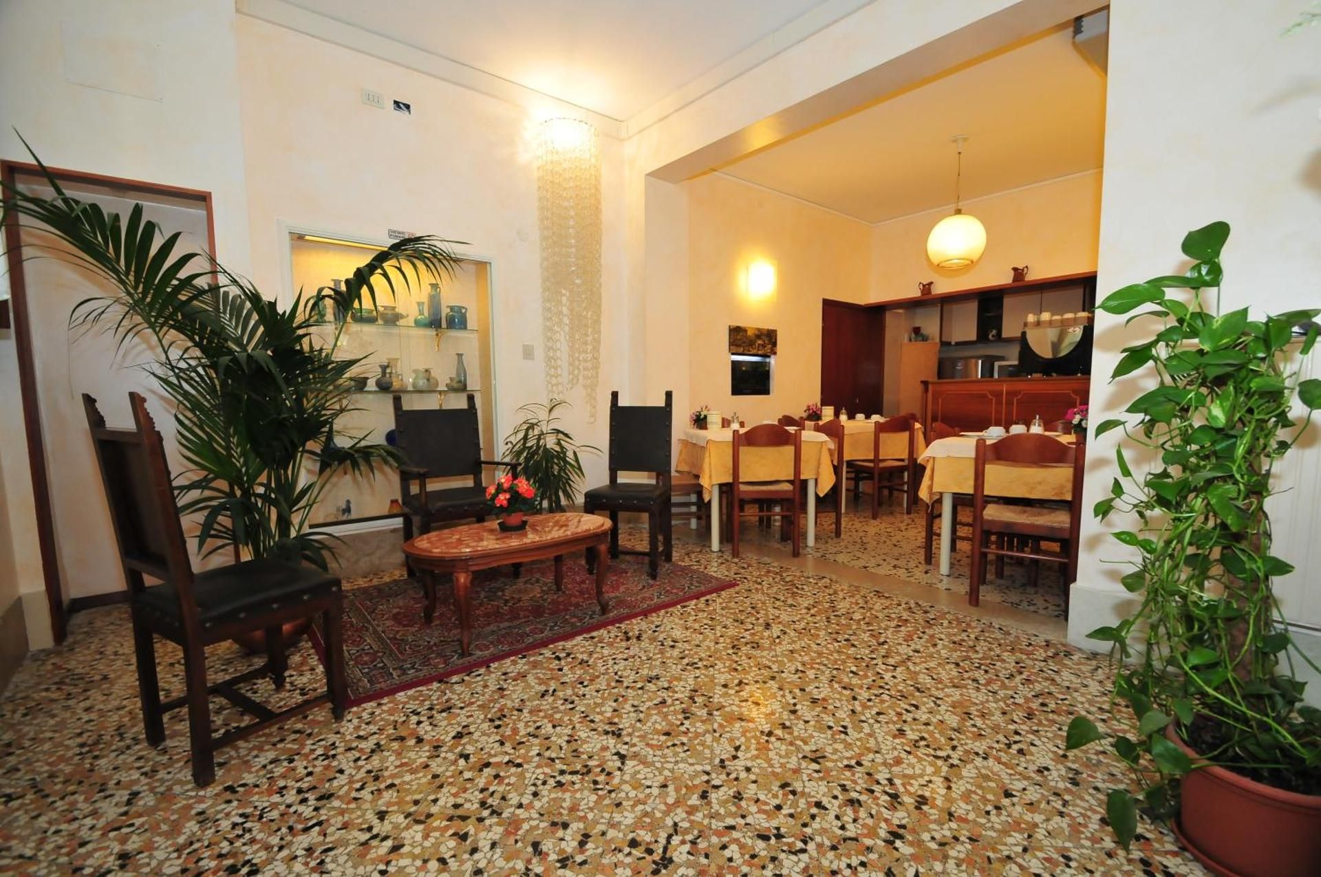 Cozy living room with patterned floor, potted plants, chairs, and a dining area in the back