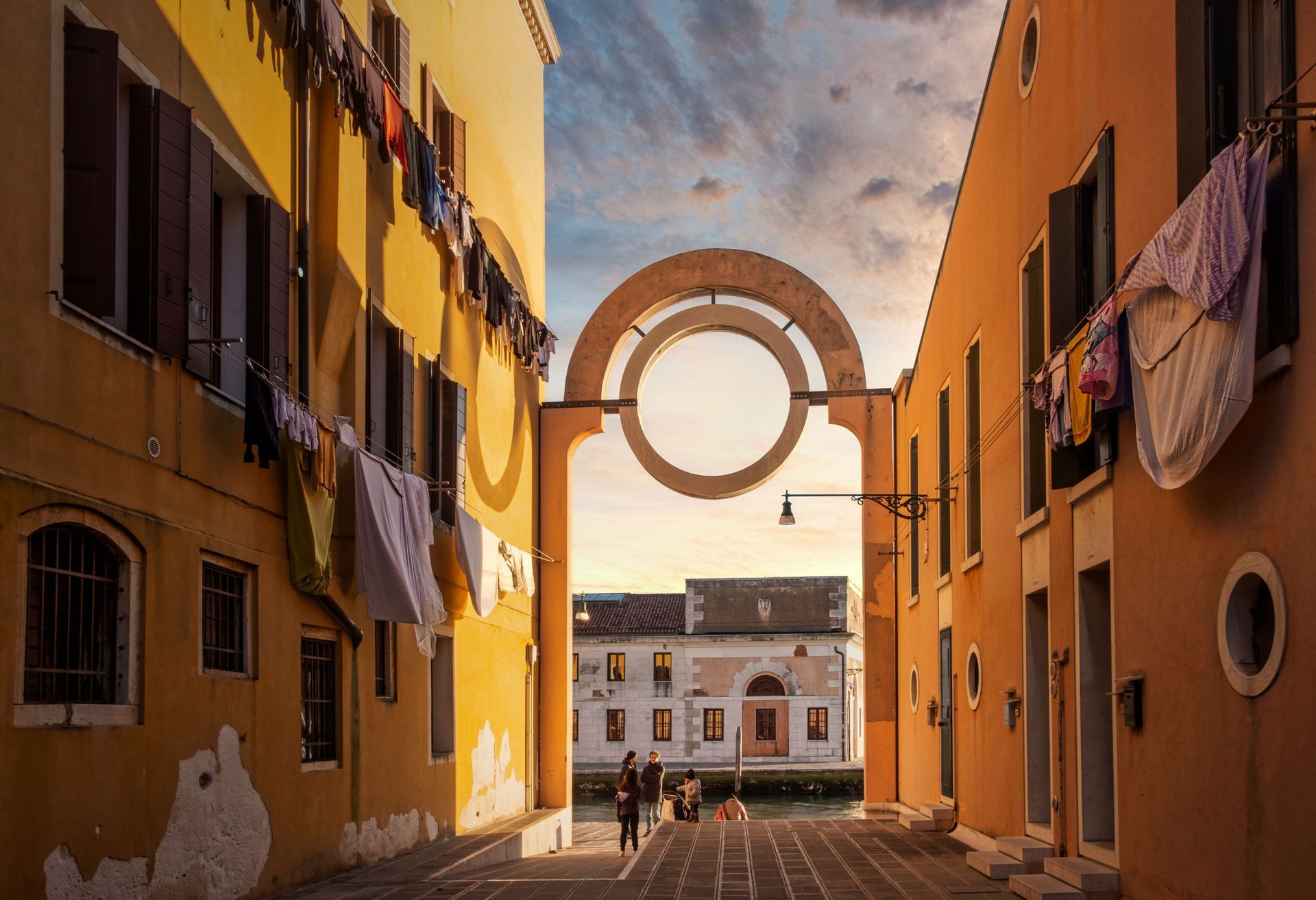 Sunlit alley between orange buildings framing a circular arch over a distant street view