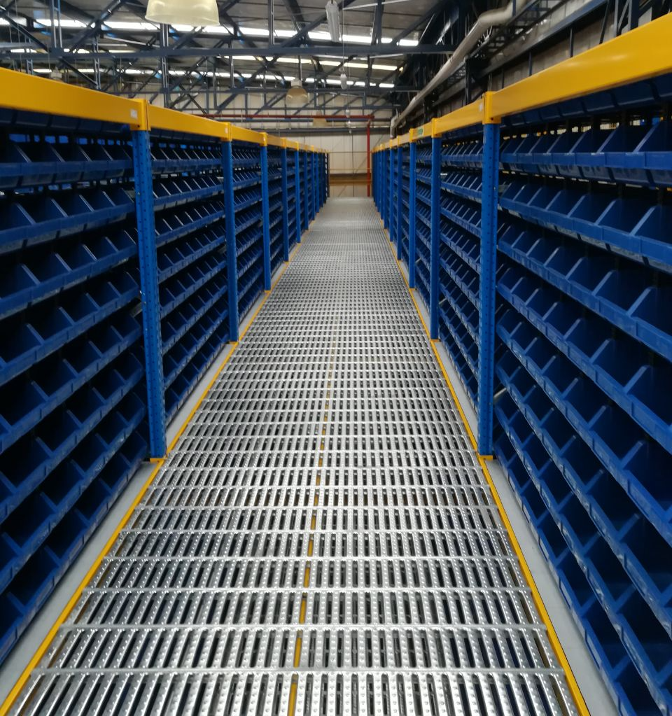 Un almacén con estantes azules y suelo de metal.