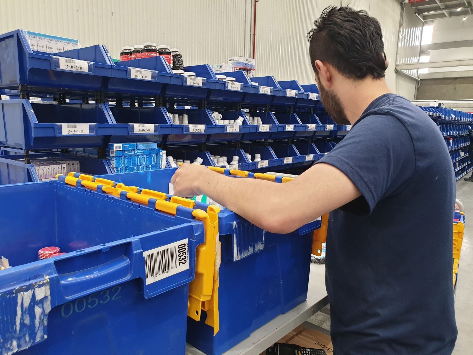 Un hombre con una camisa azul está trabajando en un almacén.