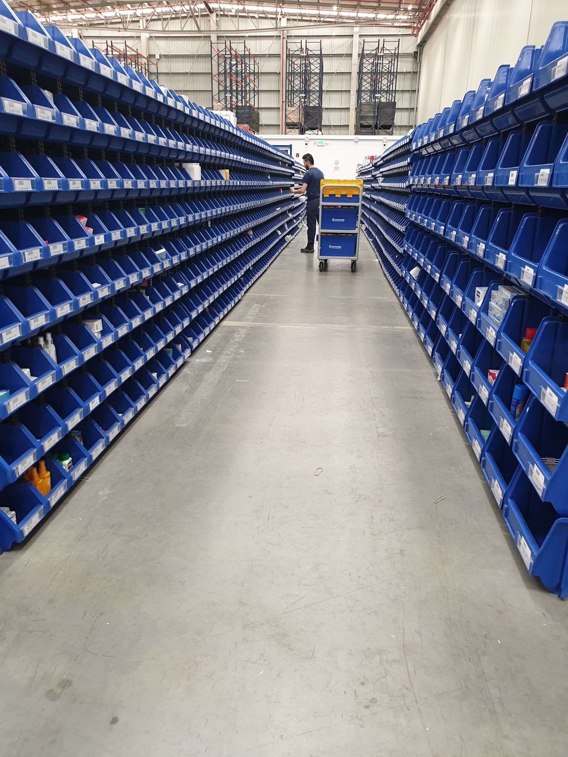 Un almacén lleno de contenedores y estantes azules.