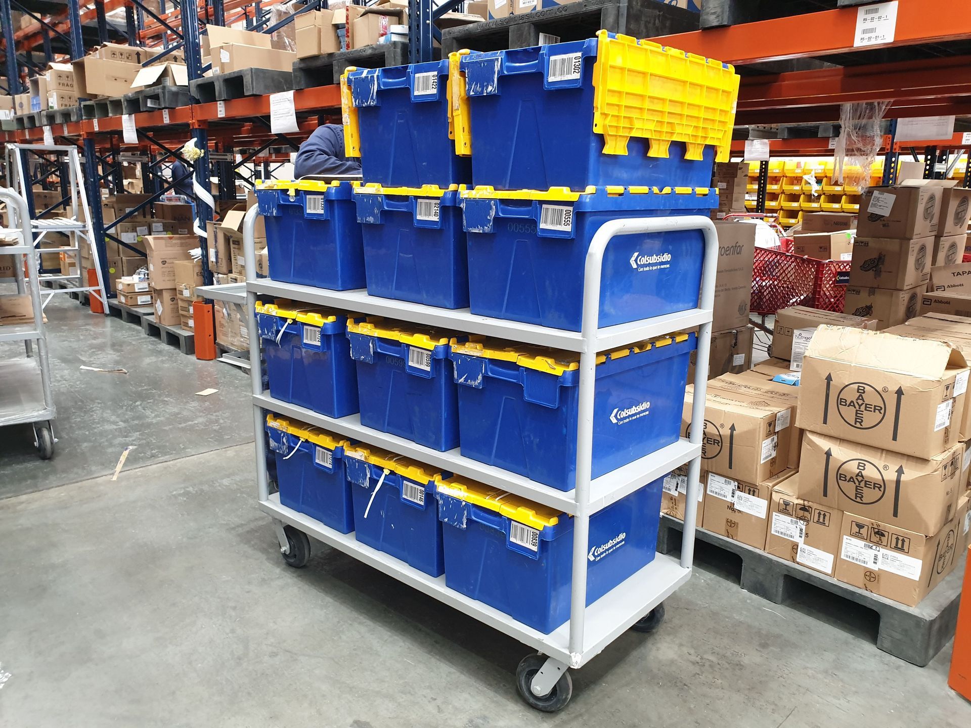 Un carrito lleno de cajas azules y tapas amarillas en un almacén.