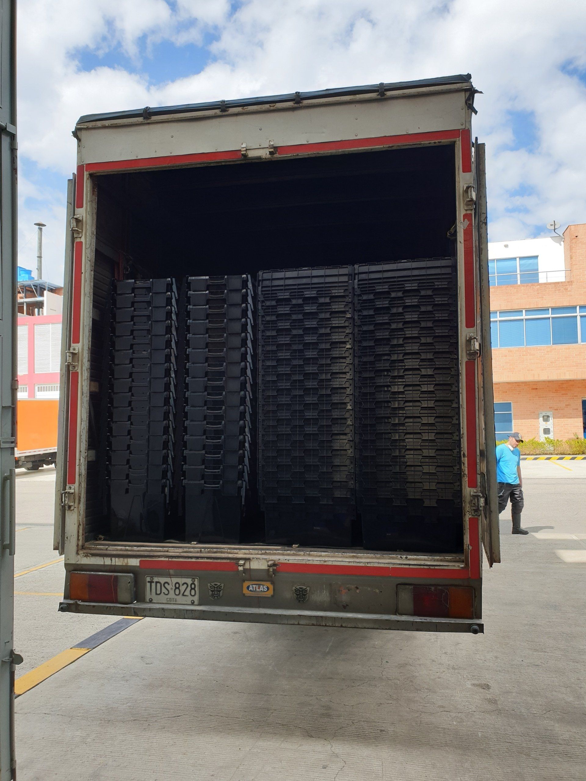 Un camión con la puerta trasera abierta está lleno de neumáticos.