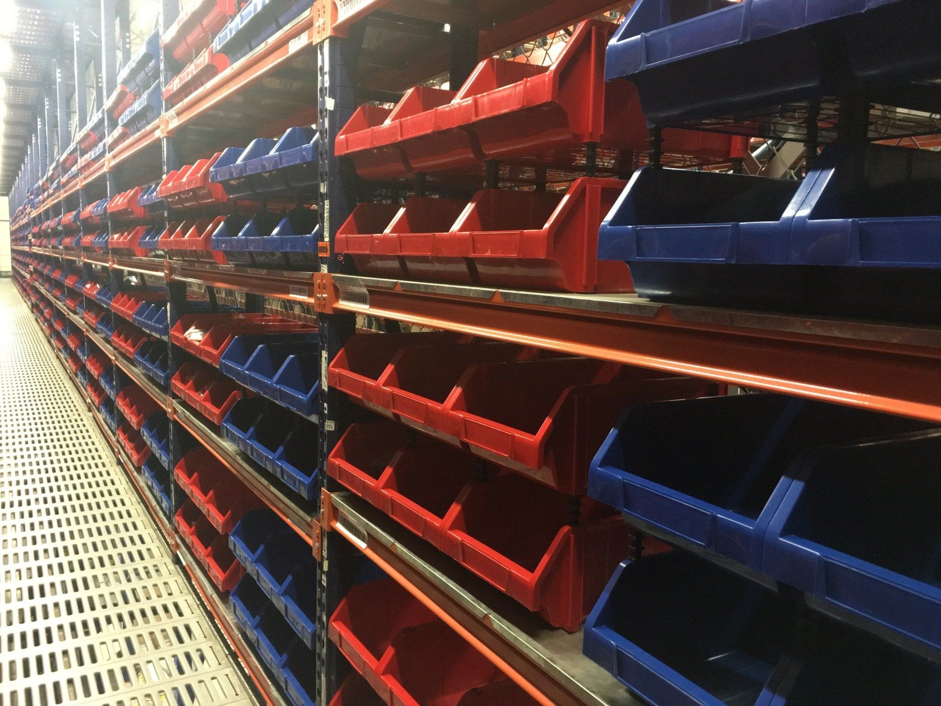 Un almacén lleno de contenedores y estantes rojos y azules.