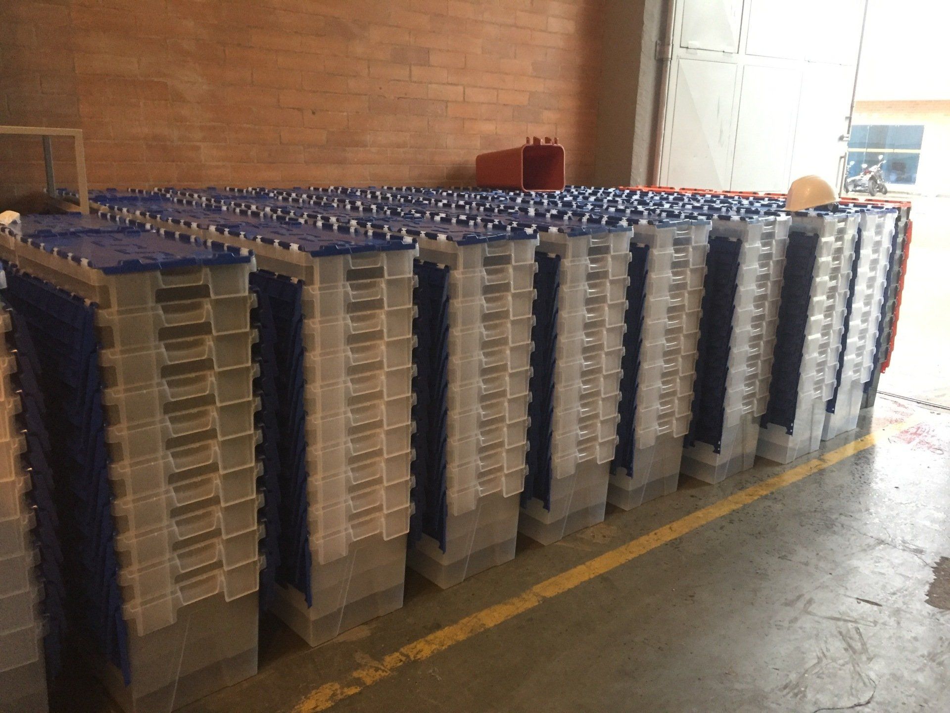 Un almacén lleno de pilas de contenedores de plástico con tapas azules.