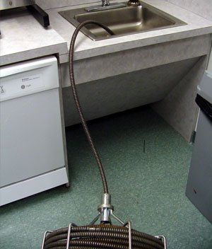 A drain snake is attached to a sink in a kitchen
