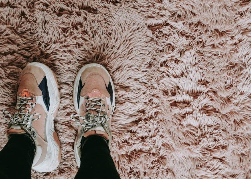Sneakers on feet standing on a beige shag rug