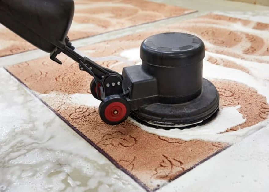 Floor scrubber cleaning a tile surface, leaving a white foamy trail