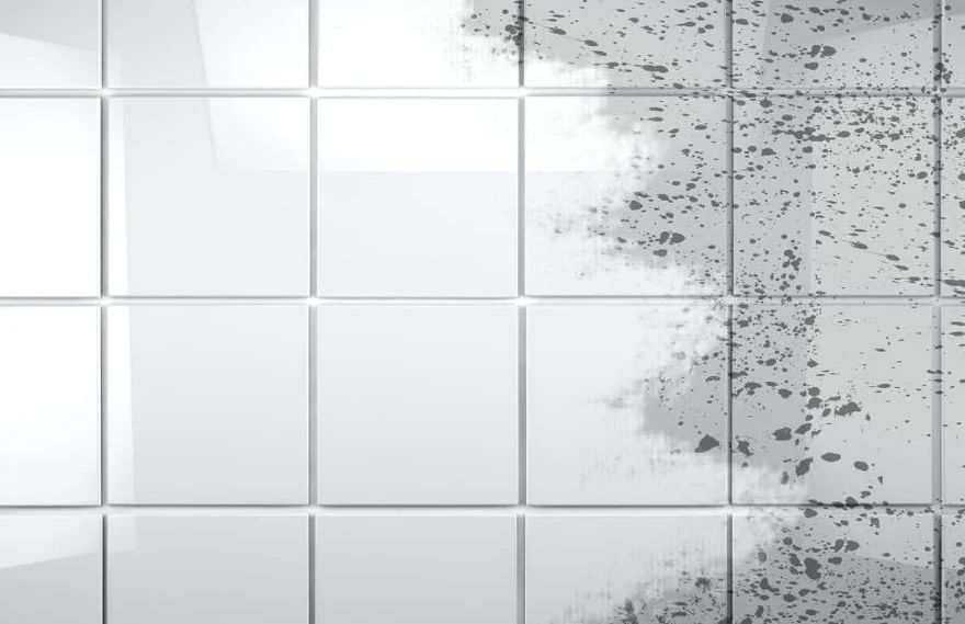 White tiled wall with a gray speckled, chipped section on the right side