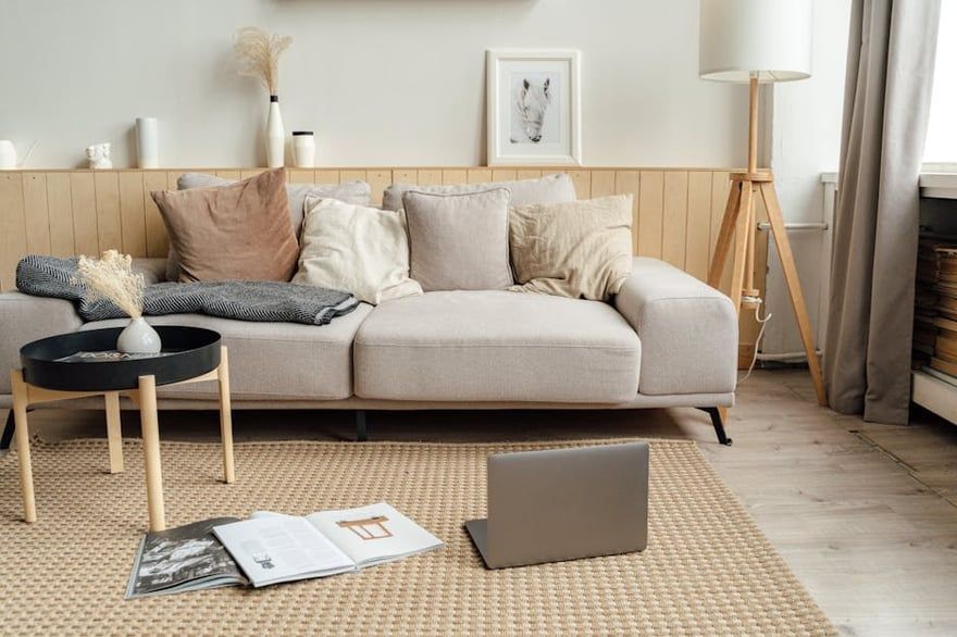 Cozy living room with beige sofa, coffee table, laptop, and an open book on a woven rug