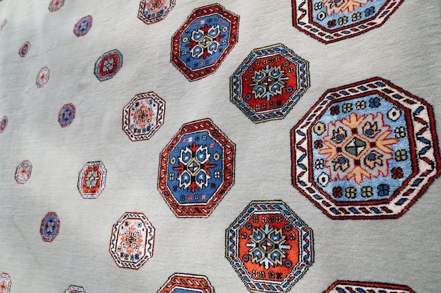 Patterned fabric with colorful geometric octagonal motifs in red, blue, and orange on a light background