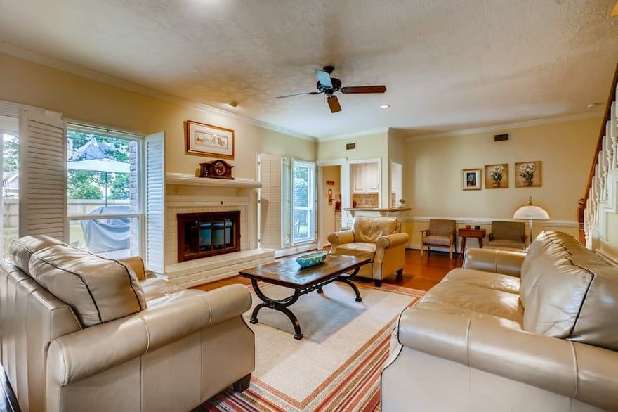 Bright living room with cream sofas, fireplace, coffee table, and sunlit windows