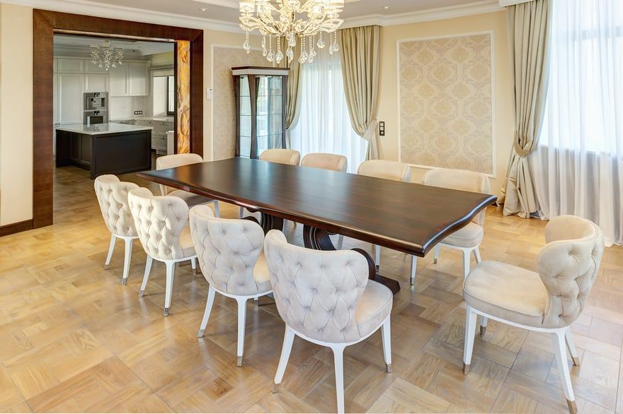 Elegant dining room with a dark wood table, upholstered chairs, chandelier, and tall windows with drapes