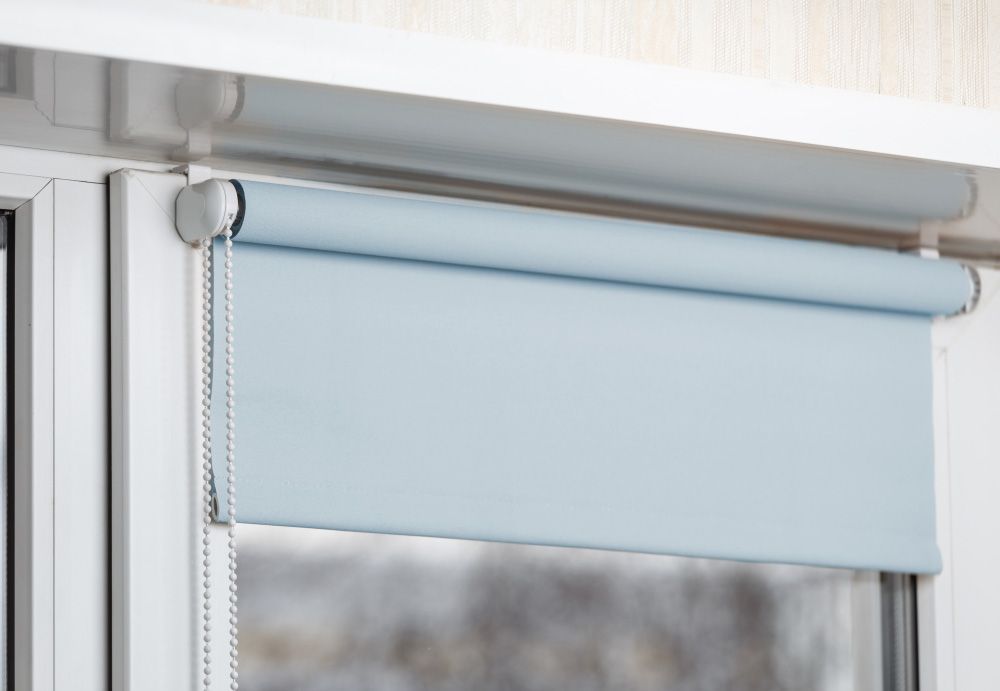 Blue Blackout Roller Blind on The White Plastic Window — Window Furnishing Services in Burleigh Heads, NSW