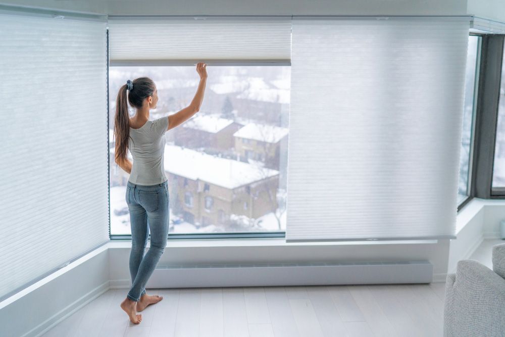 Woman Closing Cellular Shades — Window Furnishing Services in Casuarina, NSW