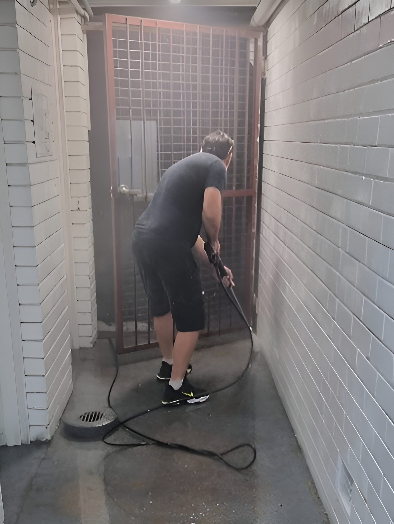 A Man is Cleaning the Floor of a Building With a High Pressure Washer — Kristal Kleen Services in Jubilee Pocket, QLD