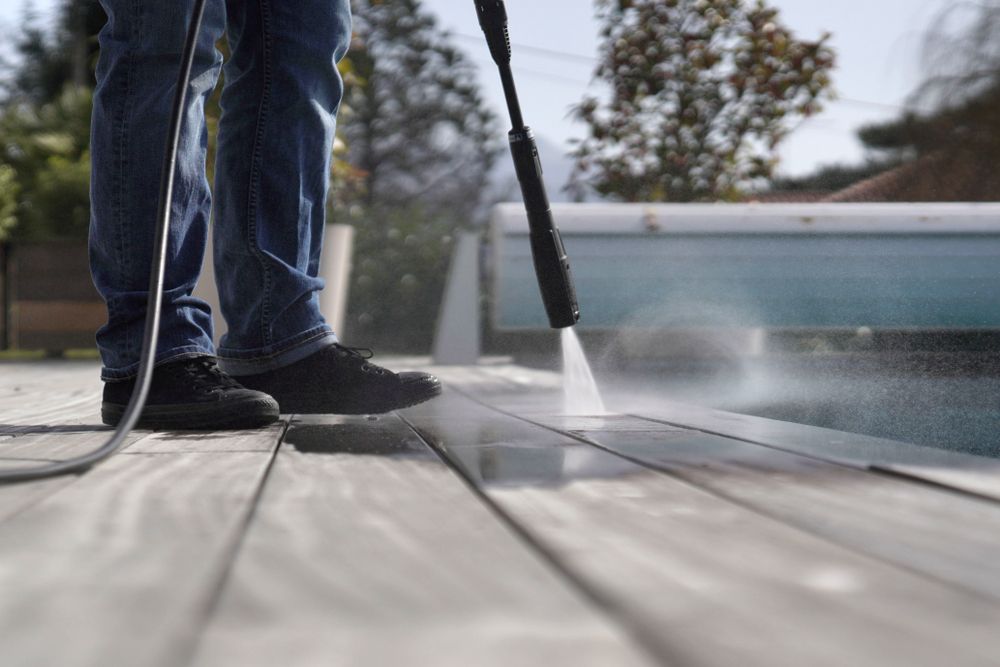 A Man is Cleaning the Floor of a Building With a High Pressure Washer — Kristal Kleen Services in Jubilee Pocket, QLD