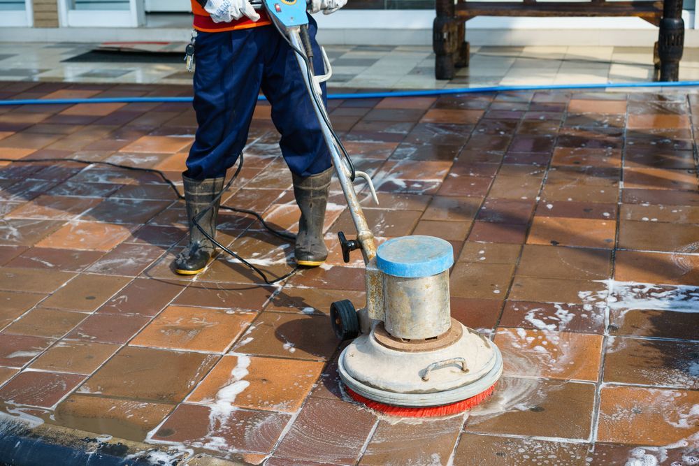 A Man Is Cleaning A Tiled Floor With A Machine — Kristal Kleen Services in Jubilee Pocket, QLD