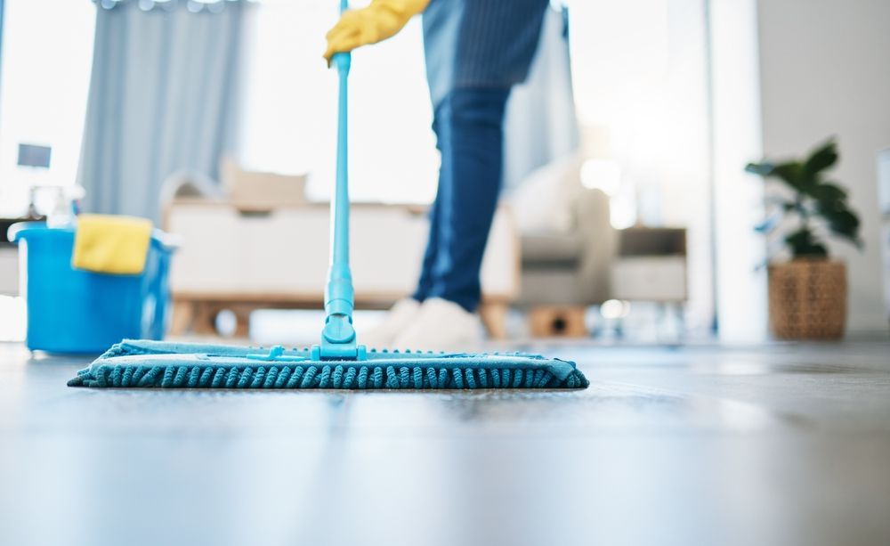 A Person Is Cleaning the Floor with A Mop in A Living Room — Kristal Kleen Services in Bowen, QLD