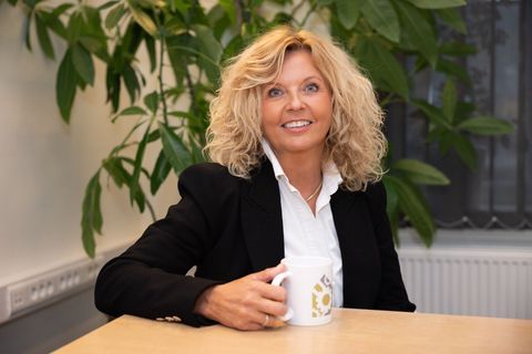 A woman is sitting at a table holding a cup of coffee.