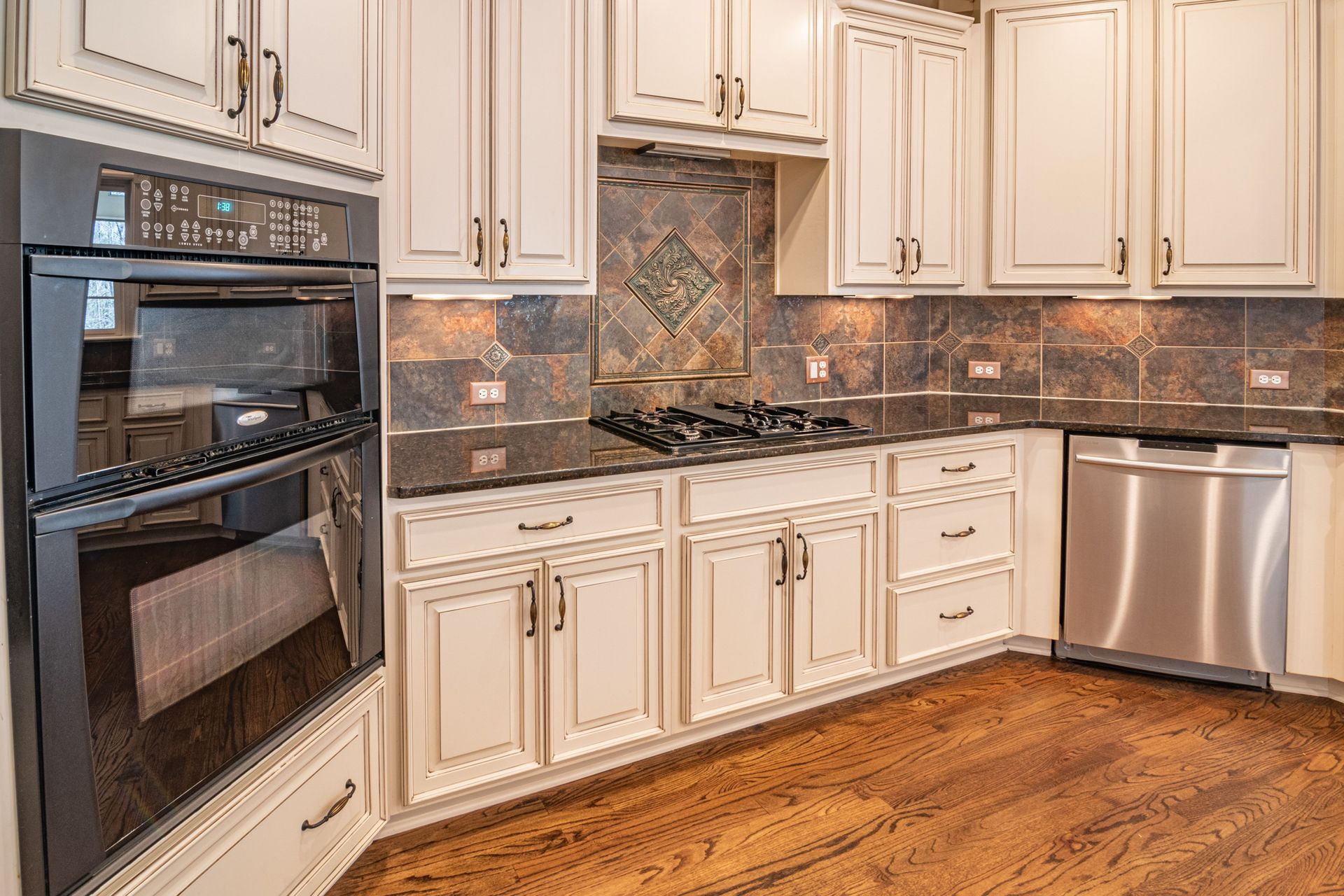 Modern kitchen with white cabinets, blue island, stainless refrigerator, and dark hardwood floors.