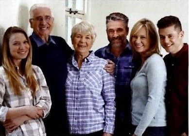 Family portrait, indoors. Six people: grandparents, adults, young adults, smiling, posing.