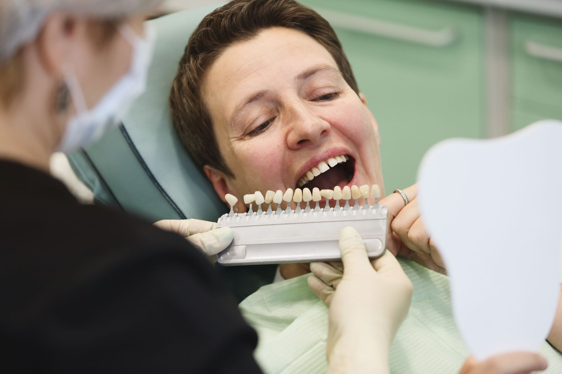 Dentist and patient choosing color for implants at the clinic.