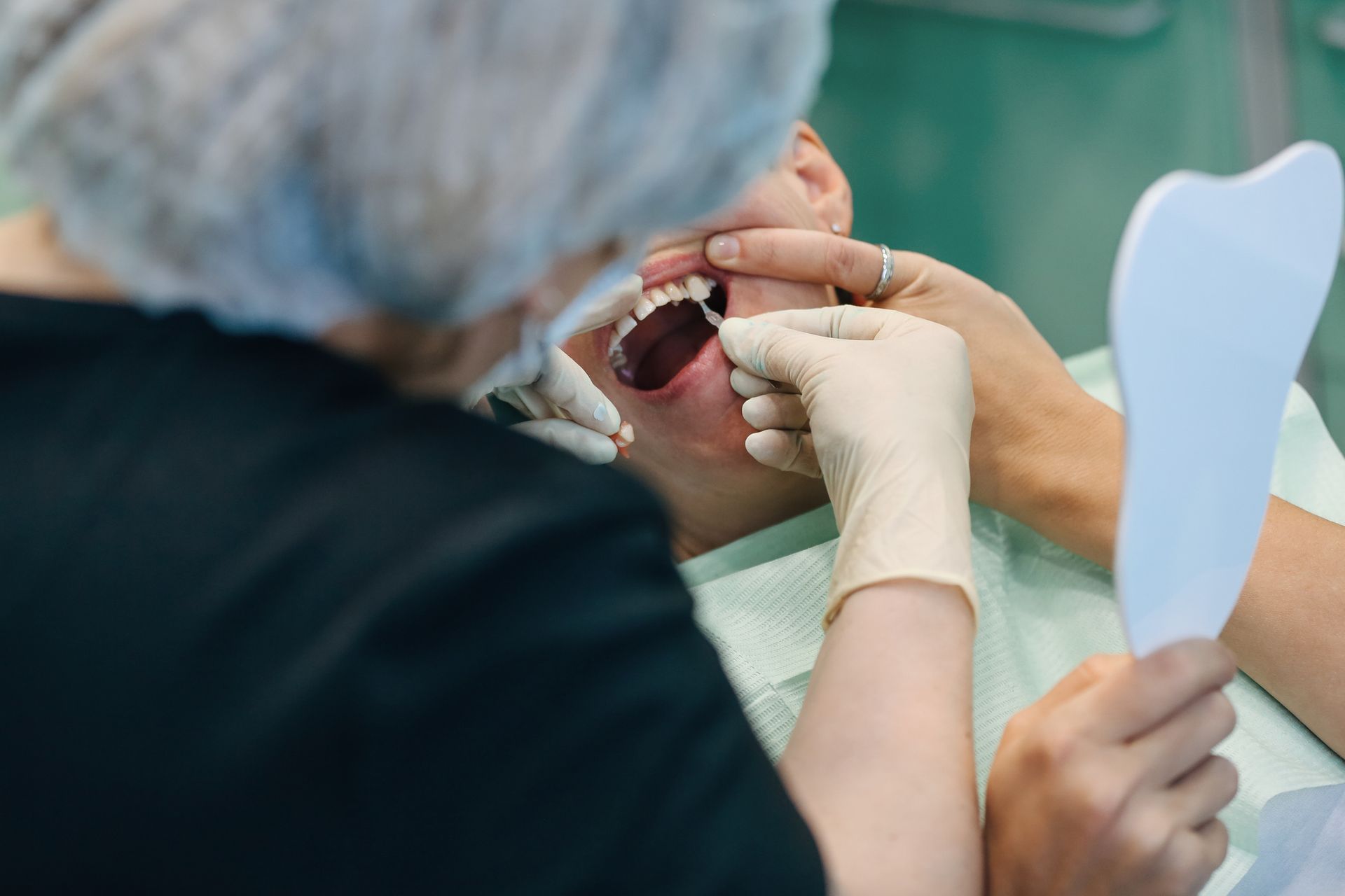 Dentist wearing protective gloves examining patient teeth for implants.