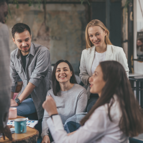 Colleagues smiling and chatting around a table in a casual office meeting