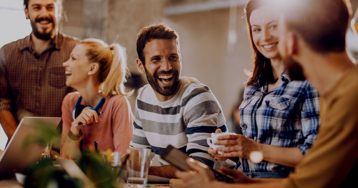 Friends chatting and smiling around a table in a warm, casual social gathering