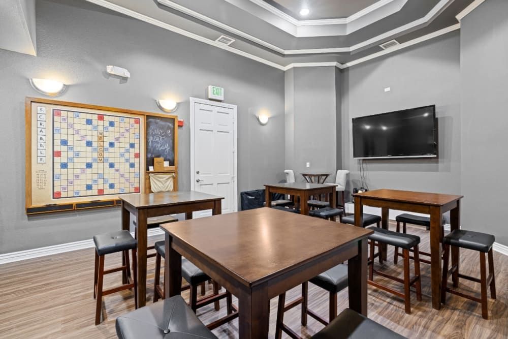 A game room with tables, chairs, a television, and a scrabble board at Marquis at Town Centre in Broomfield, CO.