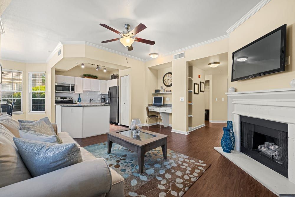Spacious living room with a couch, fireplace, television, and ceiling fan at Marquis at Town Centre in Broomfield, CO.