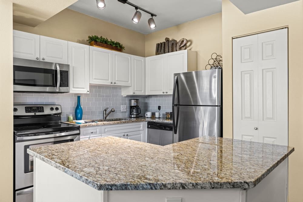 Apartment kitchen with granite counter tops, stainless steel appliances, and white cabinets at Marquis at Town Centre in Broomfield, CO.